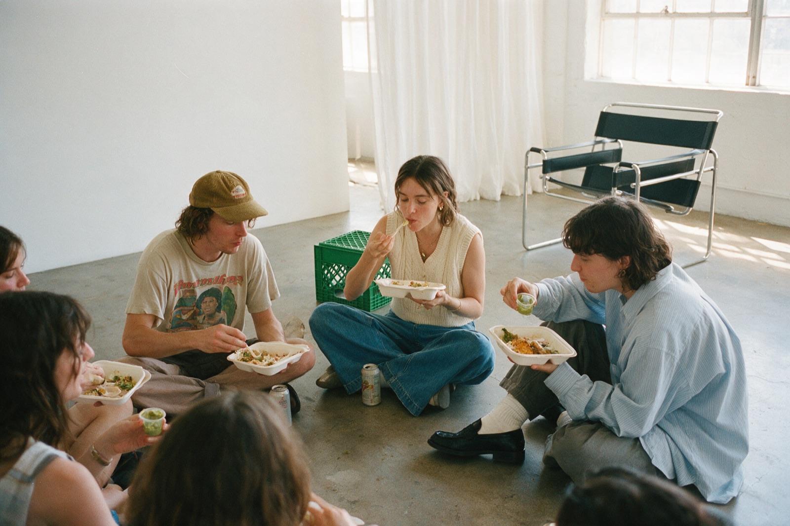 Creators sitting together on the floor, eating