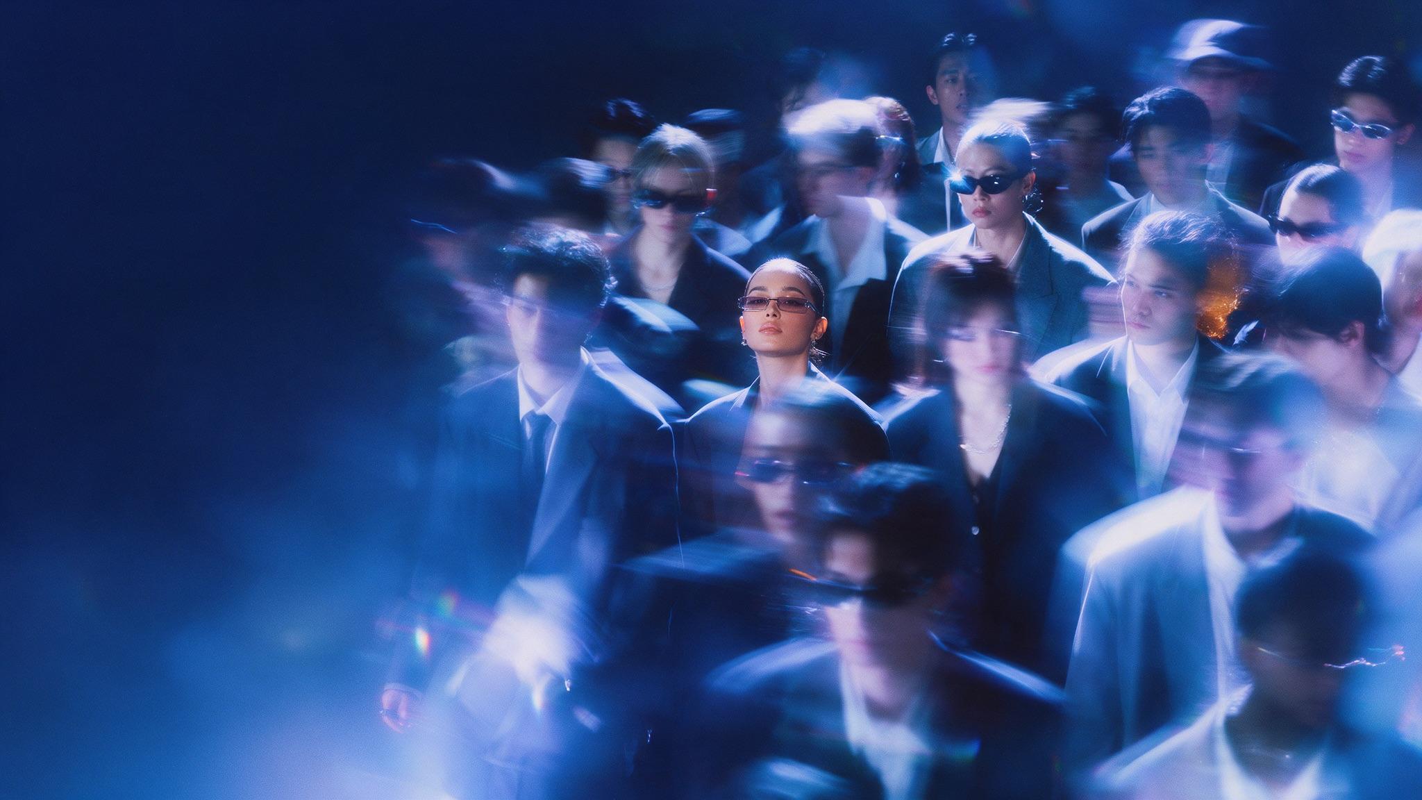 A creator in sharp focus standing in a blurred crowd